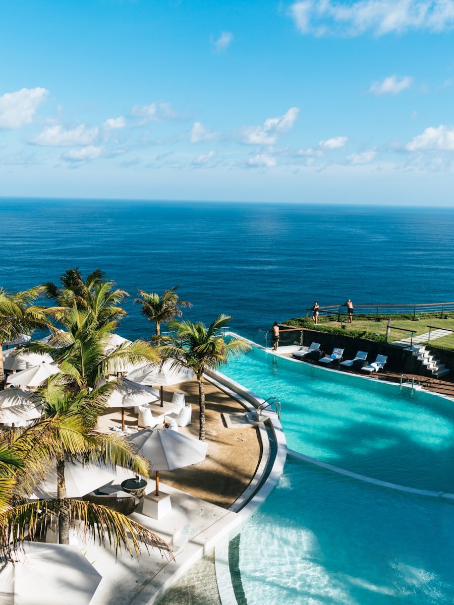 Resort-style swimming pool surrounded by palm trees by the sea